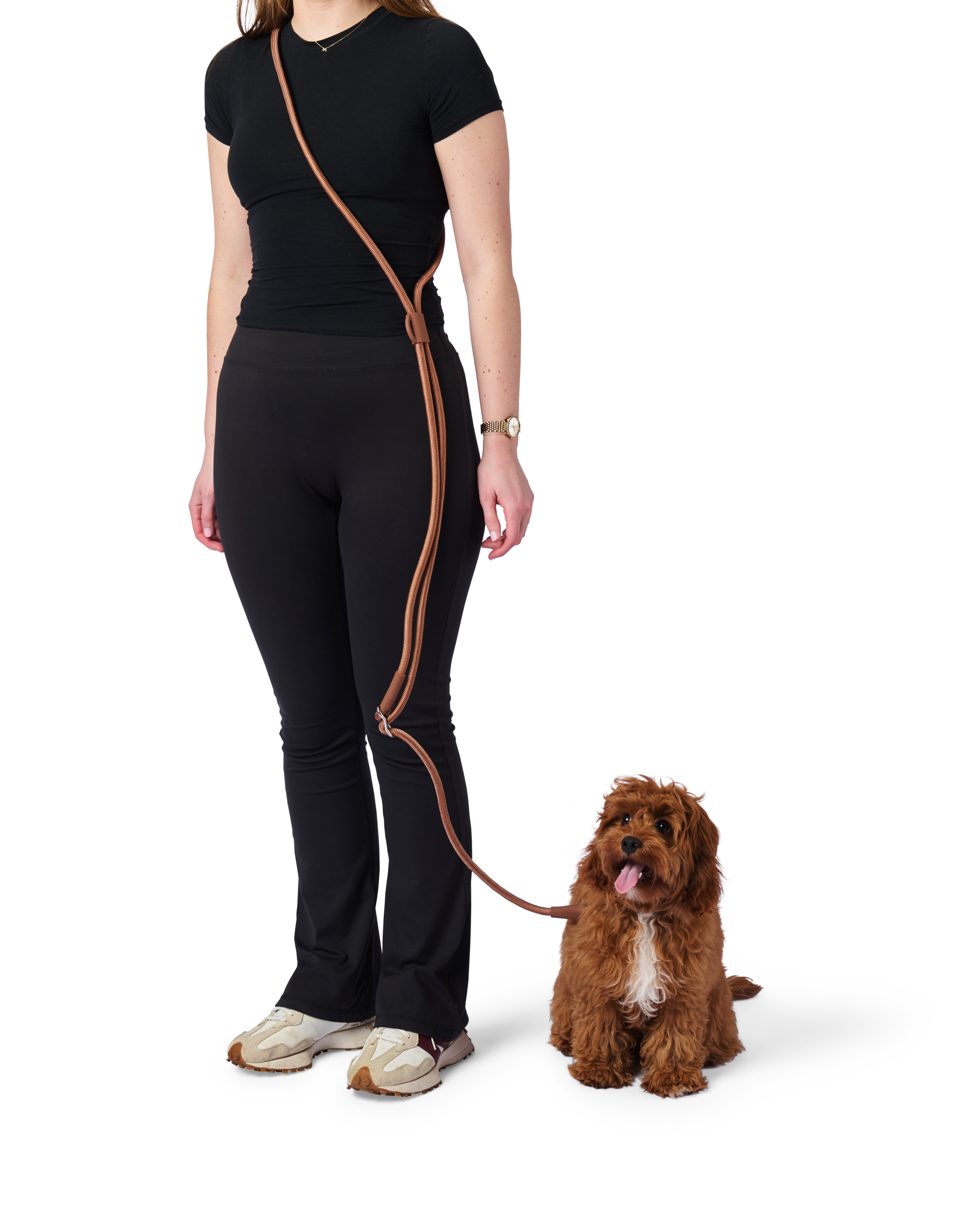 Woman in black outfit with brown leash standing next to a dog on a white background
